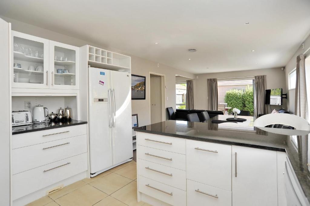 基督城Regents 94B - Christchurch Holiday Homes的厨房配有白色橱柜和白色冰箱。