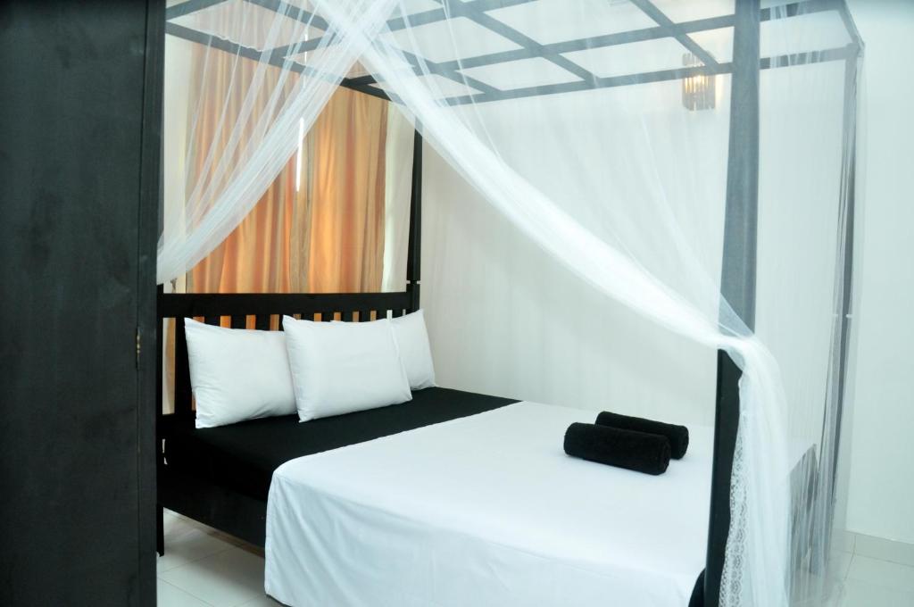 米瑞莎米瑞莎博爱考迪住宿加早餐旅馆的一间卧室配有一张带天蓬的黑白床