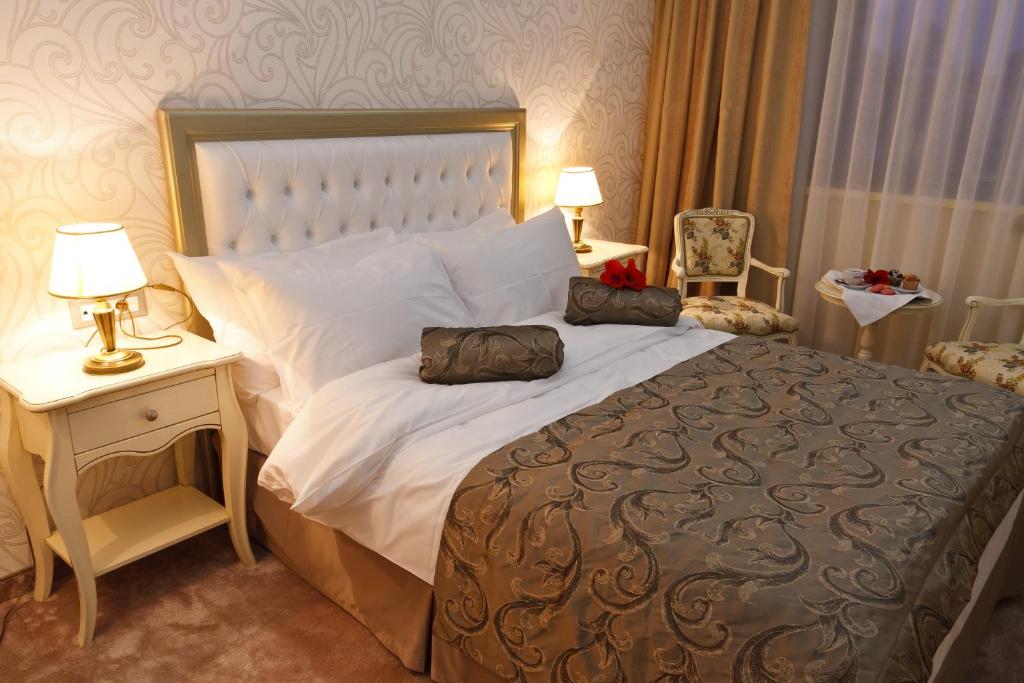罗曼Hotel Roman by Dumbrava Business Resort的一间卧室配有一张大床和一张带台灯的桌子。