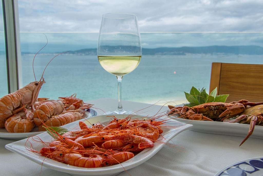 布埃乌餐厅洛雷罗酒店的一张桌子,上面放着三盘龙虾和一杯葡萄酒