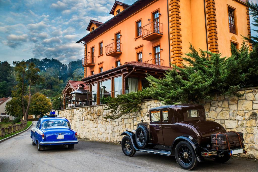 塔博尔ROMANTIK HOTEL ELEONORA的停在大楼前的一辆旧车和一辆蓝色汽车