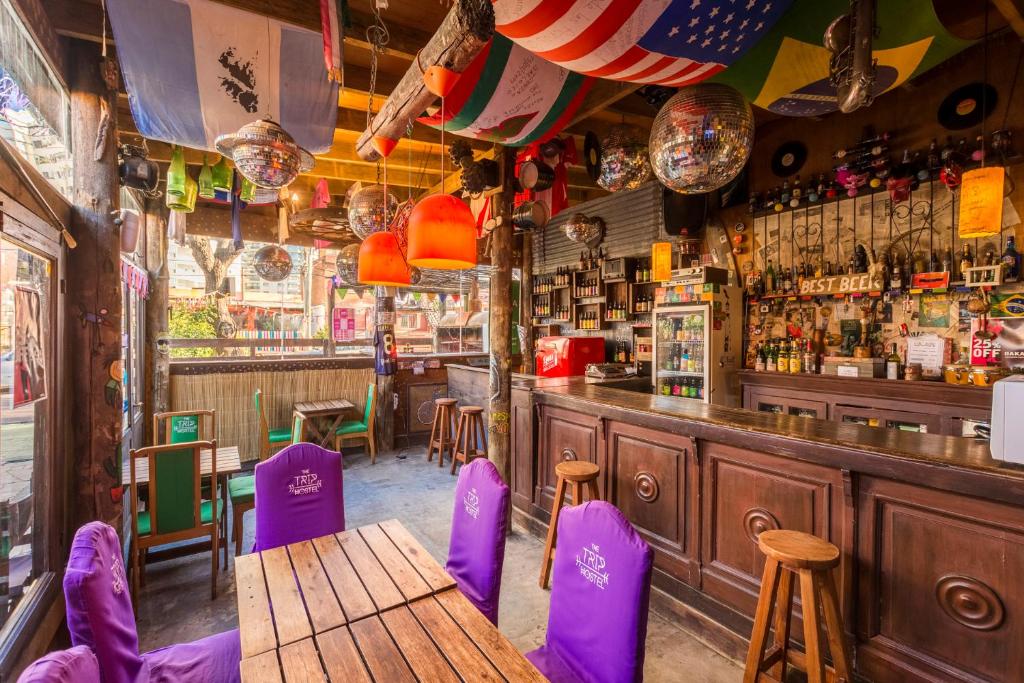 埃斯特角城The Trip Hostel的一间酒吧,配有紫色椅子和木桌