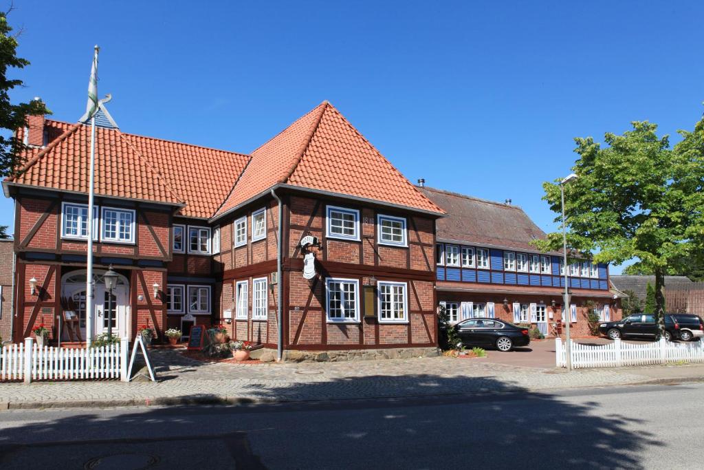 吕贝克库勒帕兰德酒店的白色栅栏的大型棕色砖砌建筑