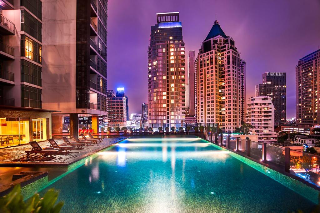 曼谷优本纳 沙通的一座在晚上拥有城市天际线的大型游泳池