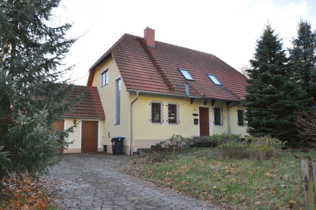 GlashütteFerienhaus Weber的黄色的房子,有红色的屋顶和车道