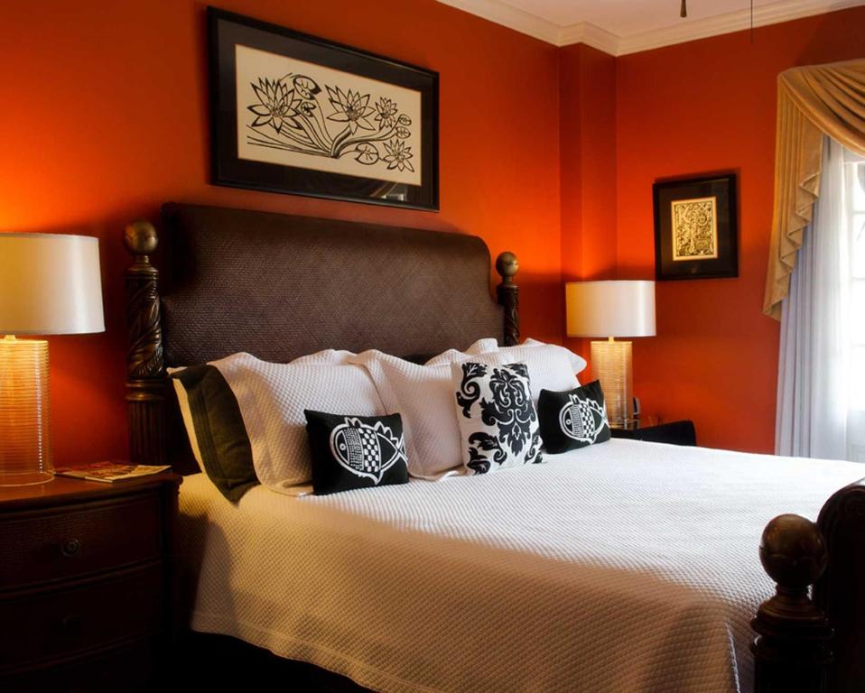杰克逊Old Capitol Inn的一间卧室拥有橙色的墙壁,配有一张带枕头的床。