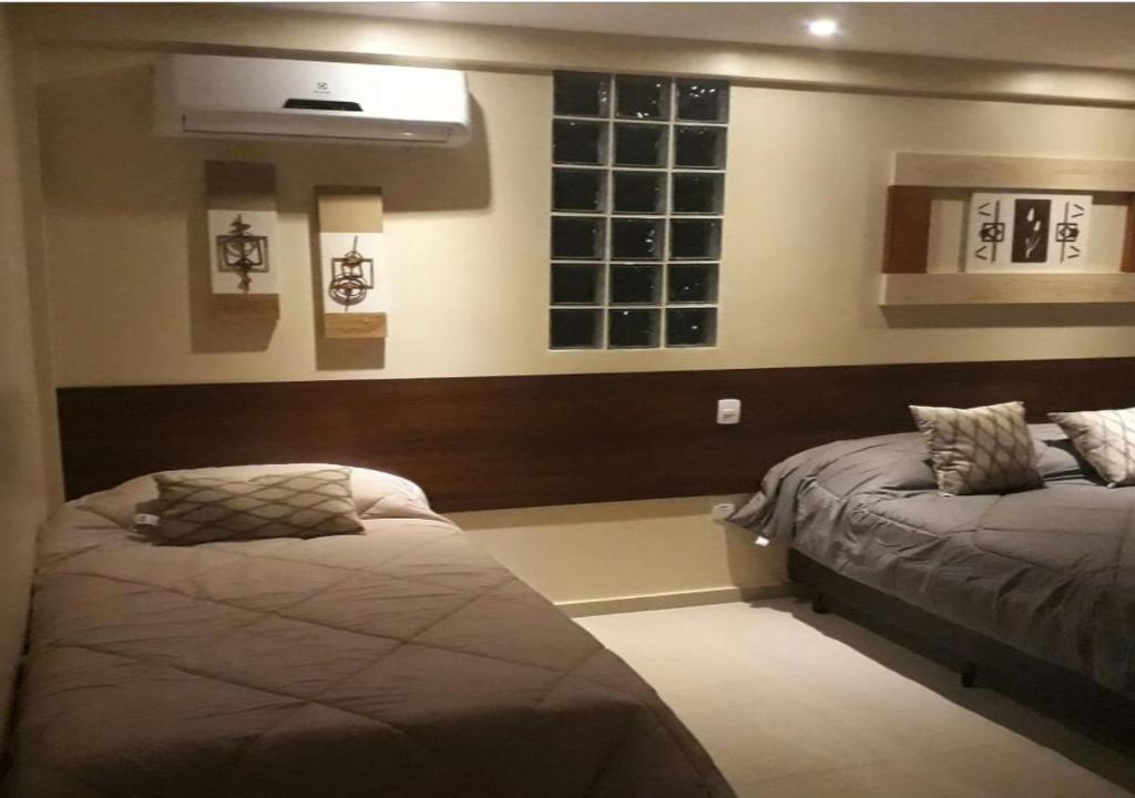 布希奥斯Suítes Praias de Búzios的一间卧室设有两张床和窗户。