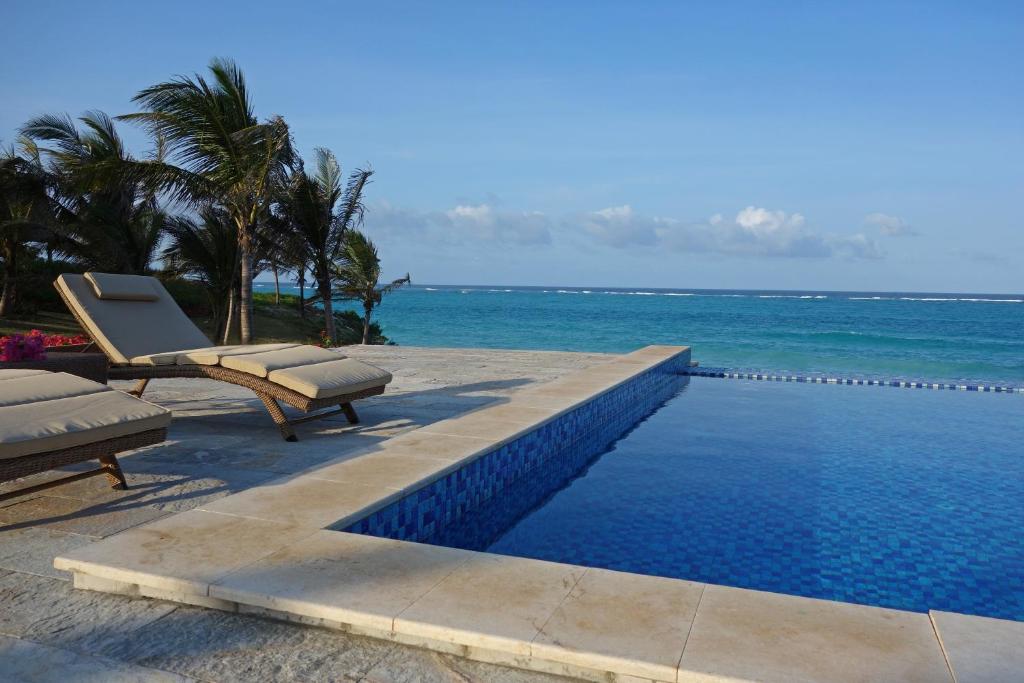 米查维Zawadi Hotel, Zanzibar的一个带2把躺椅的游泳池和海洋