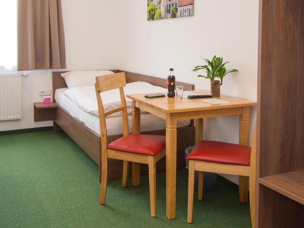 维也纳新城得胜经济型住宿加早餐旅馆的客房设有书桌、带桌椅的床