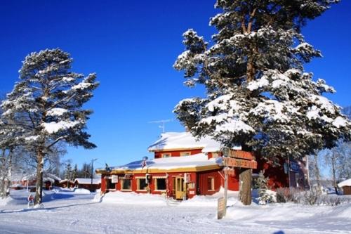 高尔卡万胡德旅游中心酒店的两棵树掩埋在雪中的房子