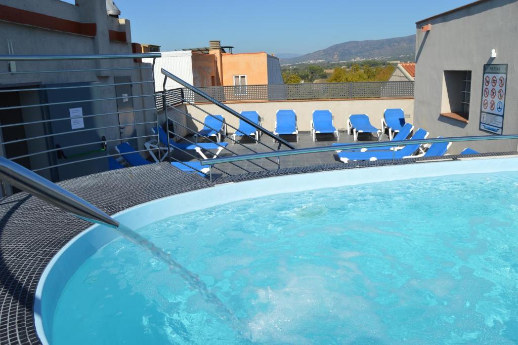 罗萨斯希乌塔德拉酒店的一座带椅子的建筑的顶部游泳池