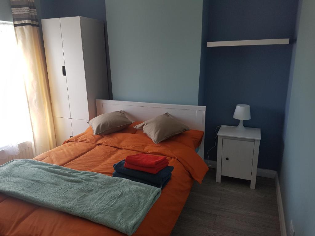 塞特福德St Giles, Thetford, 2BR House的蓝色卧室,配有带橙色毯子的床