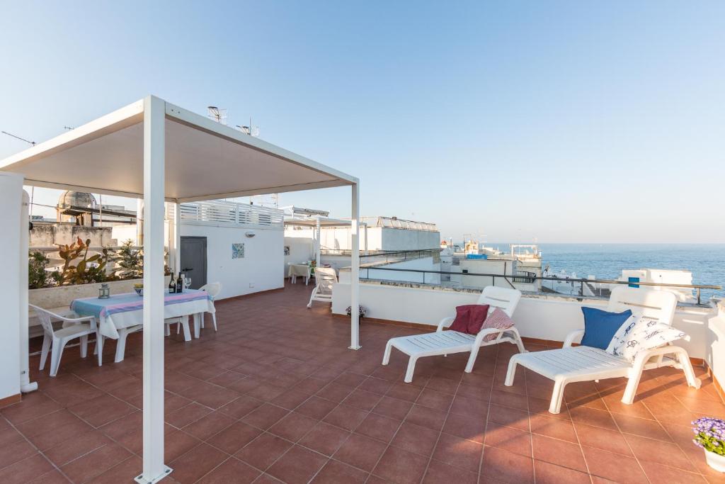 莫诺波利Appartamento Helios的一个带白色桌椅的庭院和大海