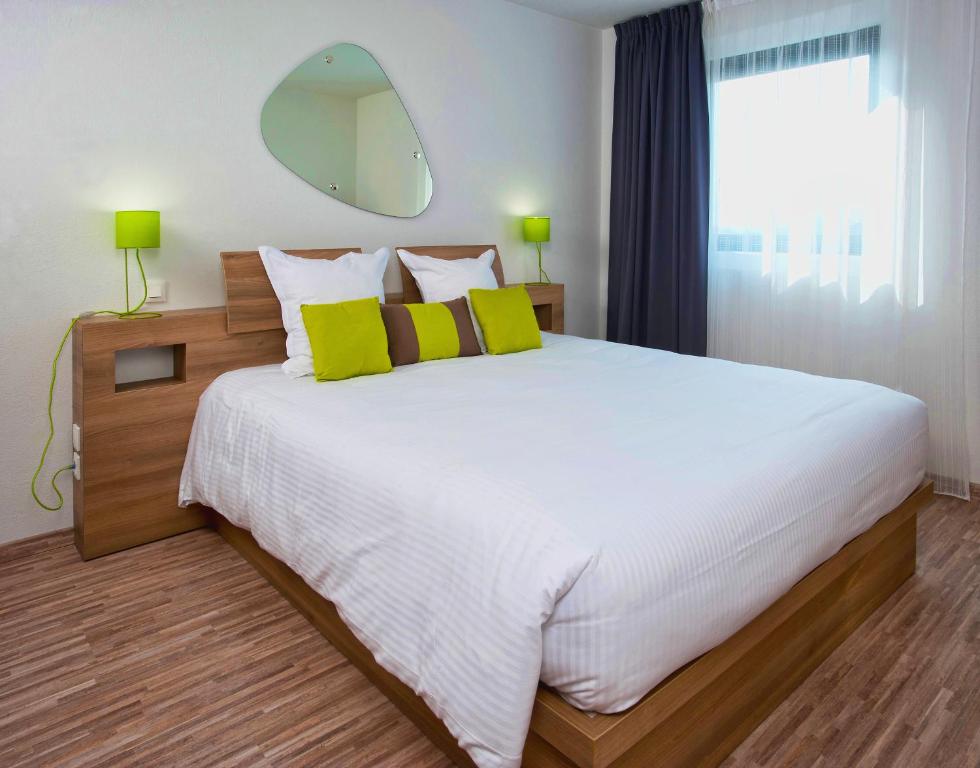 梅里尼亚克Ténéo Apparthotel Bordeaux Mérignac - Aéroport的卧室配有一张带黄色枕头的大型白色床。