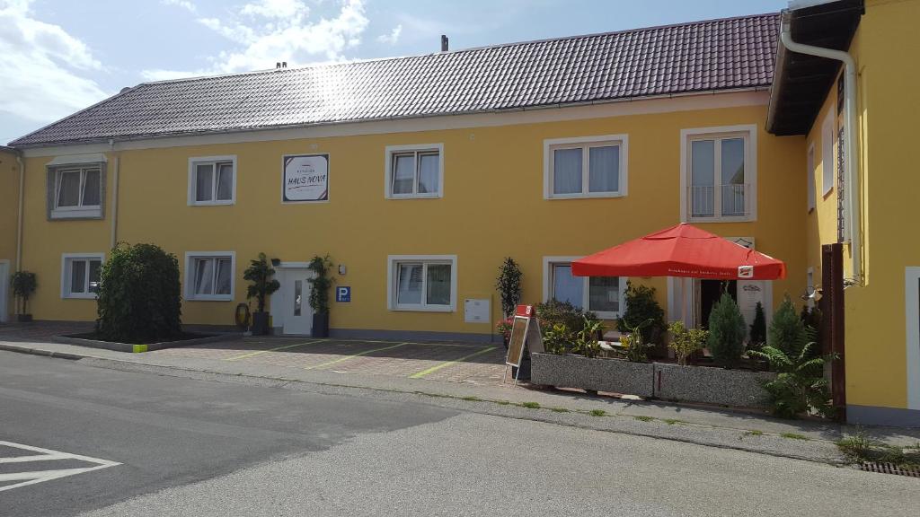 维也纳新城诺瓦住宿加早餐旅馆的街道旁的黄色建筑,带有红伞