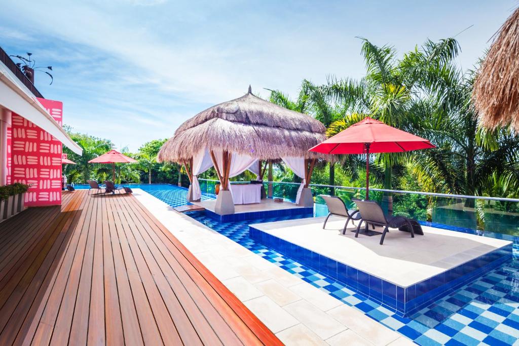 布兰卡滩巴鲁得可麦仑酒店&度假村 - 全包 的一个带椅子和遮阳伞的游泳池的度假酒店