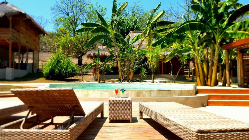 吉利特拉旺安Jati Village, Party Hostel and Bungalows的一个带游泳池、两把椅子和一张桌子的度假胜地