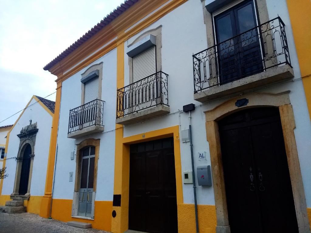 SardoalCasa Sardoal的白色和黄色的建筑,设有黑色的门和阳台