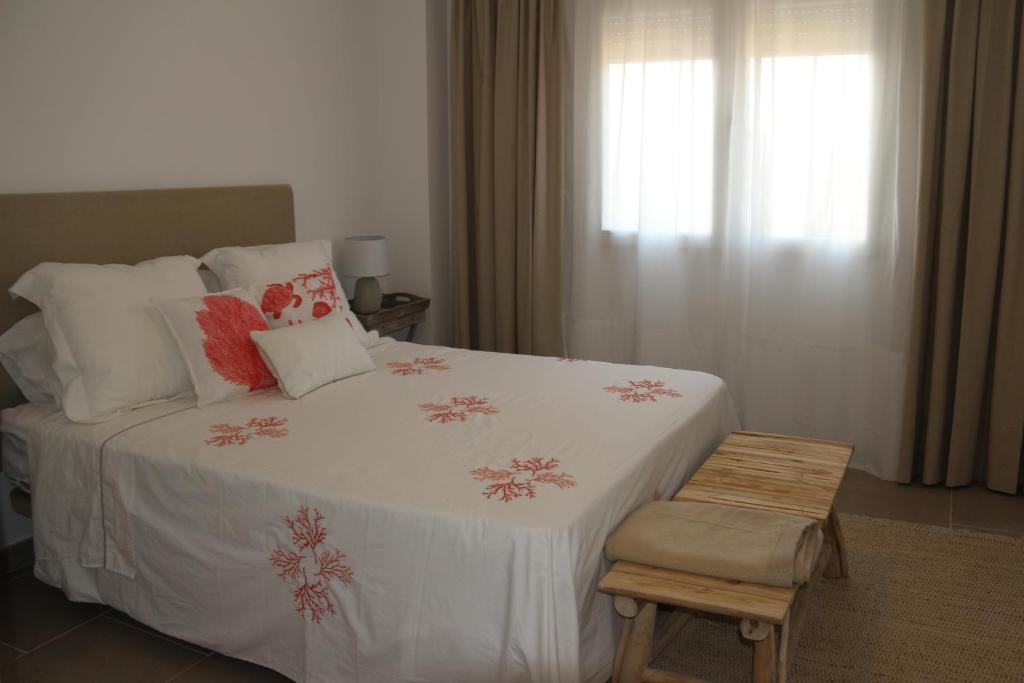 萨阿拉德洛斯阿图内斯NEW!! Bonito adosado en Zahara de los Atunes的卧室配有带枕头和椅子的白色床