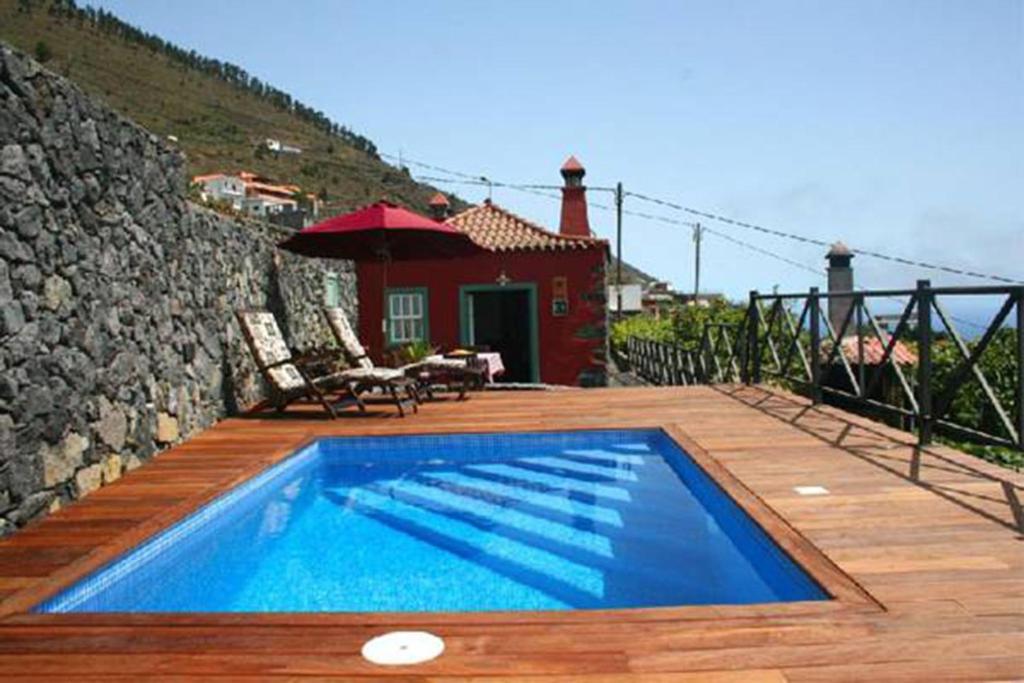 丰卡连特德拉帕尔马Casa Rural La Caldera的一个带房子的木甲板上的游泳池