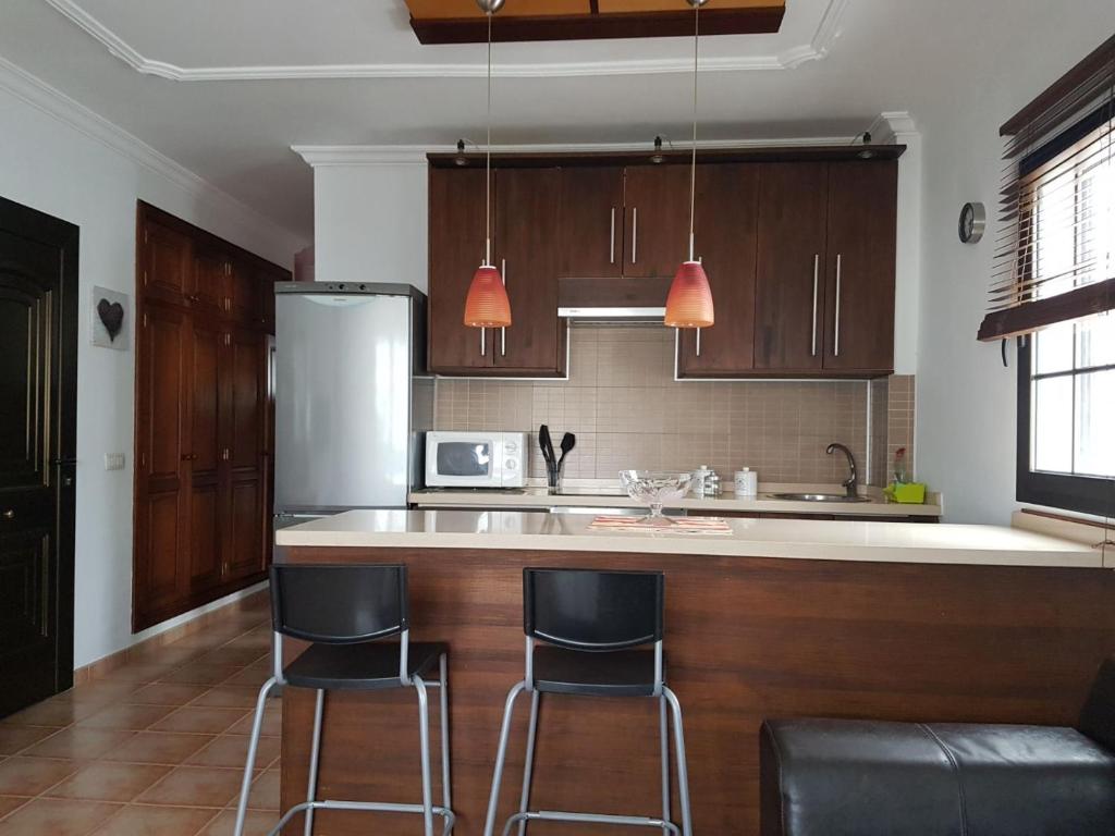 阿列塔Casa Garita Beach的厨房配有2把吧台凳和1台冰箱