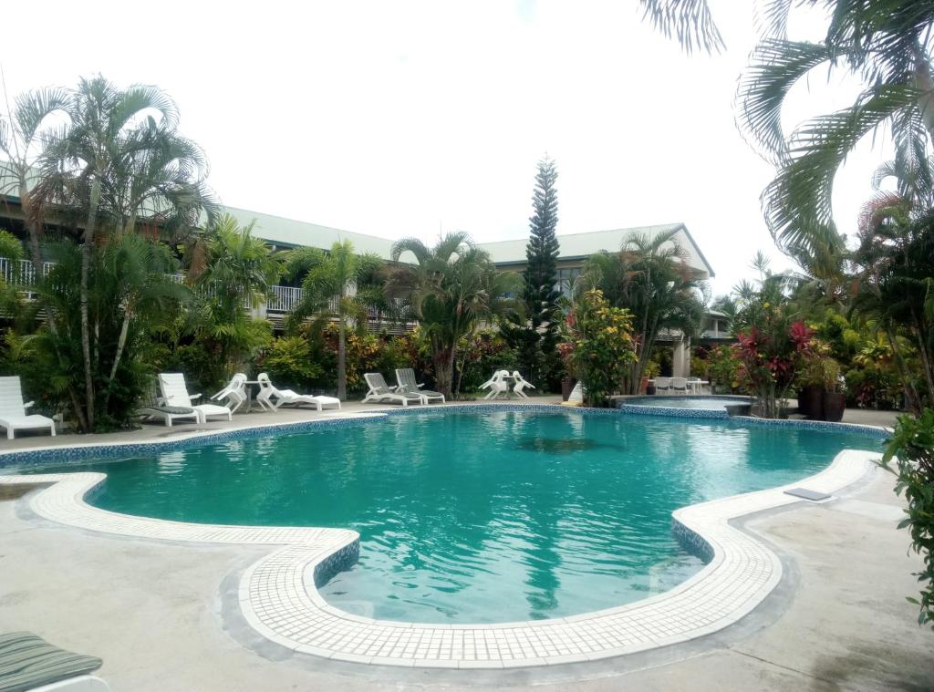阿皮亚萨摩亚美连利亚酒店的度假村内的游泳池,带椅子和棕榈树