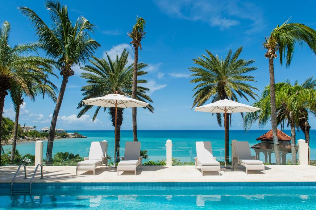圣约翰斯蓝色海域Spa度假酒店的一个带椅子和遮阳伞的游泳池以及大海
