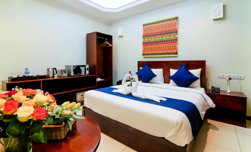 达累斯萨拉姆坦桑行政套房酒店的一间卧室配有一张床和一张鲜花桌