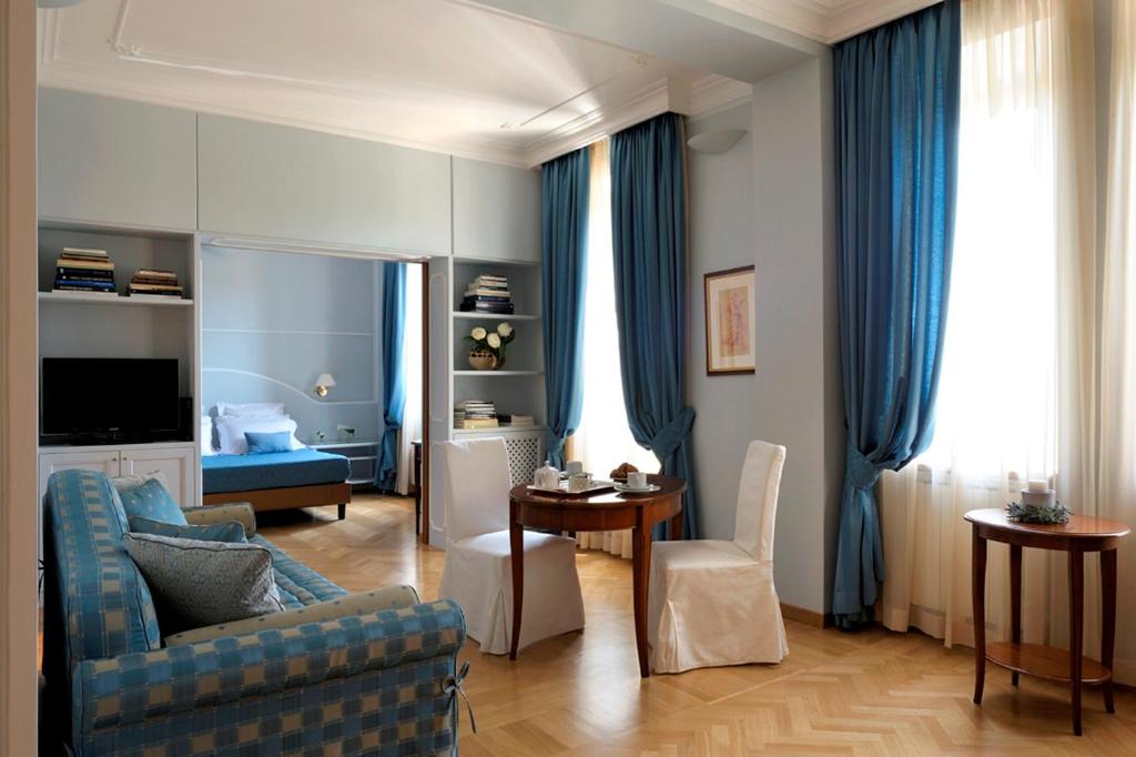 罗马德亚套房罗马酒店的客厅配有蓝色窗帘和蓝色沙发