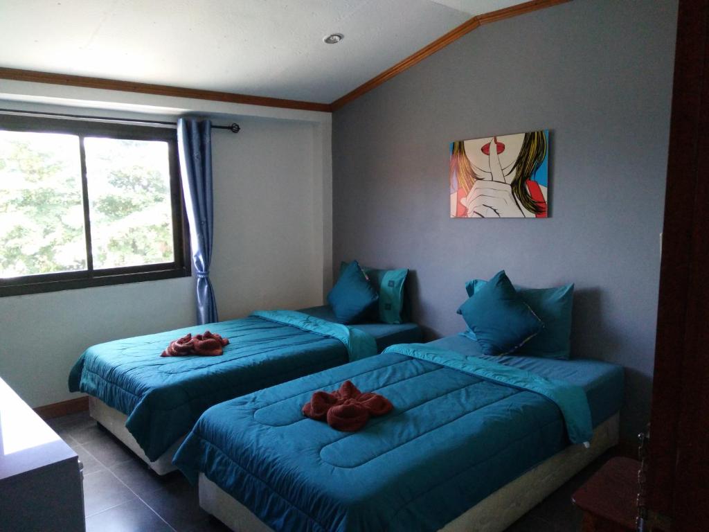 沙美岛可卡维村2@可萨梅特经济型酒店的配有蓝色床单和红色玫瑰的客房内的两张床