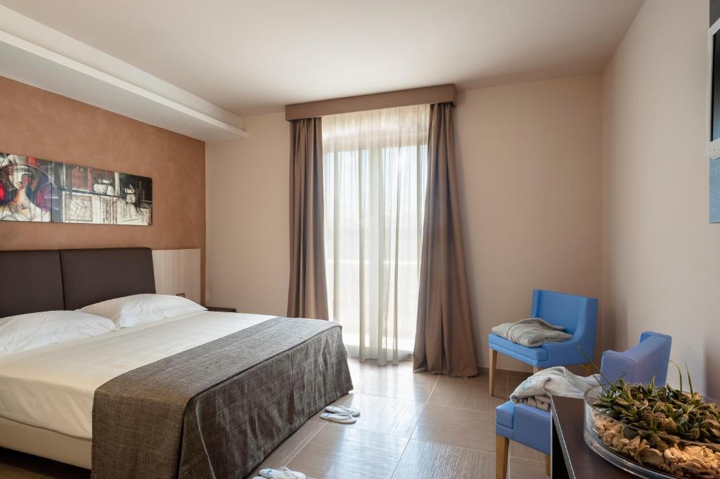 切萨雷奥港乐敦套房酒店的一间卧室配有一张床和两张蓝色椅子