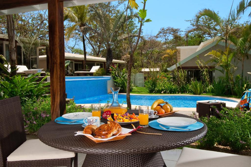 塔马林多The Breeze Hotel & Villas的游泳池旁的餐桌上摆放着食物和饮料