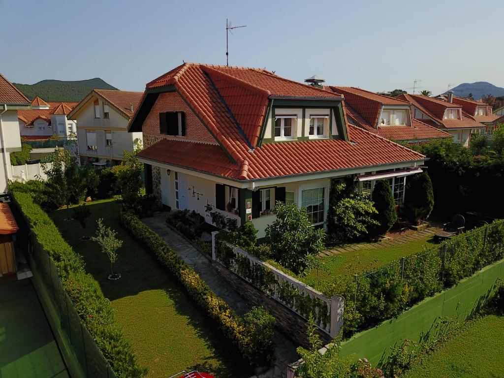 阿尔戈尼奥斯Chalet Argoños的一座红色屋顶的房子和一个院子