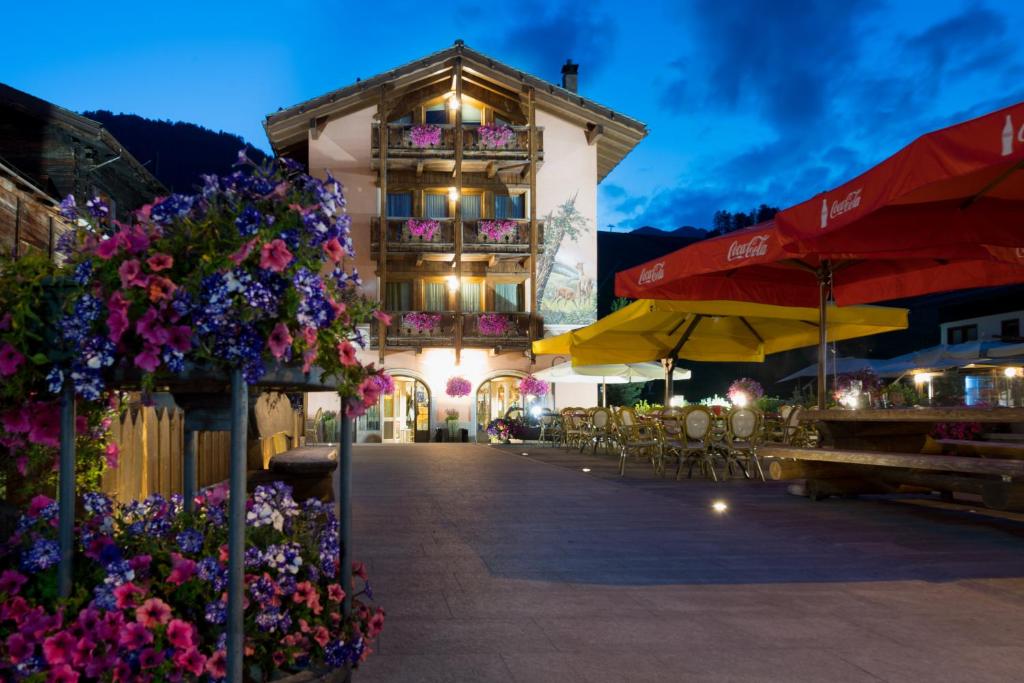 利维尼奥B&B Via Vai的一座带花卉、桌子和遮阳伞的建筑