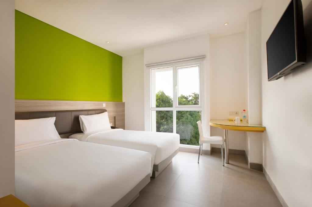 泗水Amaris Hotel Darmo Surabaya的绿墙客房的两张床