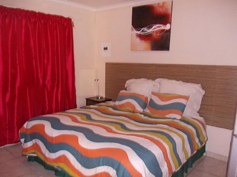 Brakpan迎宾旅馆的一间卧室配有一张带彩色条纹毯子的床