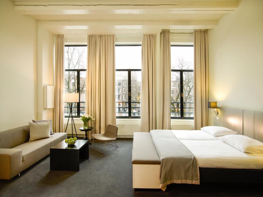 阿姆斯特丹Hapimag Apartments Amsterdam的一间卧室配有一张床、一张沙发和窗户。