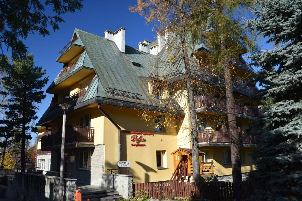 扎科帕内Dafne Zakopane的一座大型黄色房屋,设有绿色屋顶