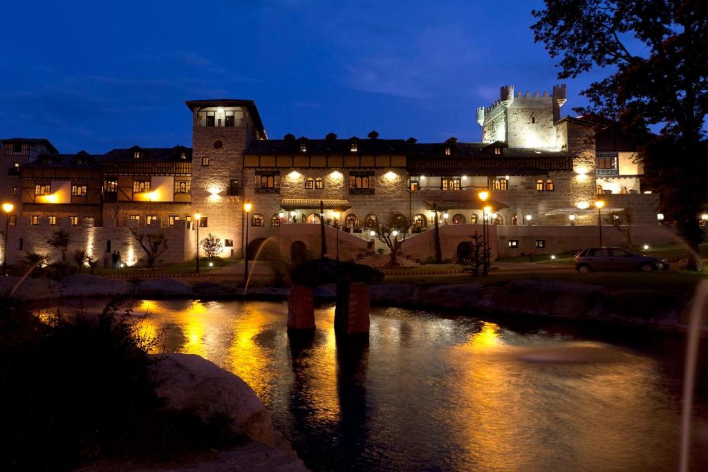 拉阿贝尔卡圣堂修道院温泉酒店的一座大建筑,在晚上,前面有河
