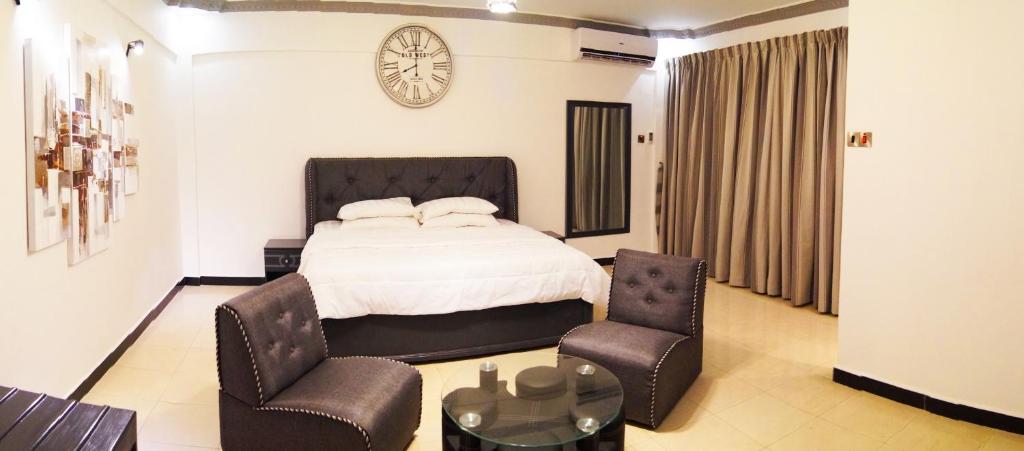 达累斯萨拉姆Econo Lodge的一间卧室配有一张床、两把椅子和一个时钟
