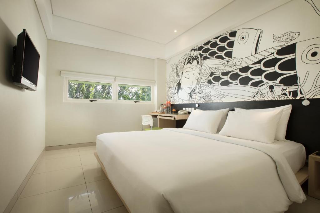 库塔格兰德玛斯普拉斯机场酒店的卧室配有白色大床和壁画