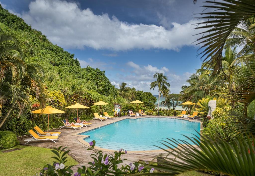 Vunaniu斐济威尔斯利度假酒店的一个带椅子和遮阳伞的游泳池