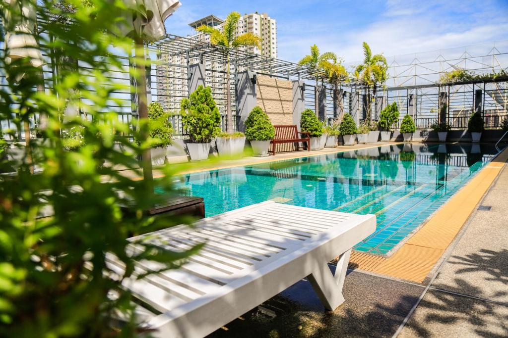 曼谷Northgate Ratchayothin的一座游泳池,旁边是一座白色长凳