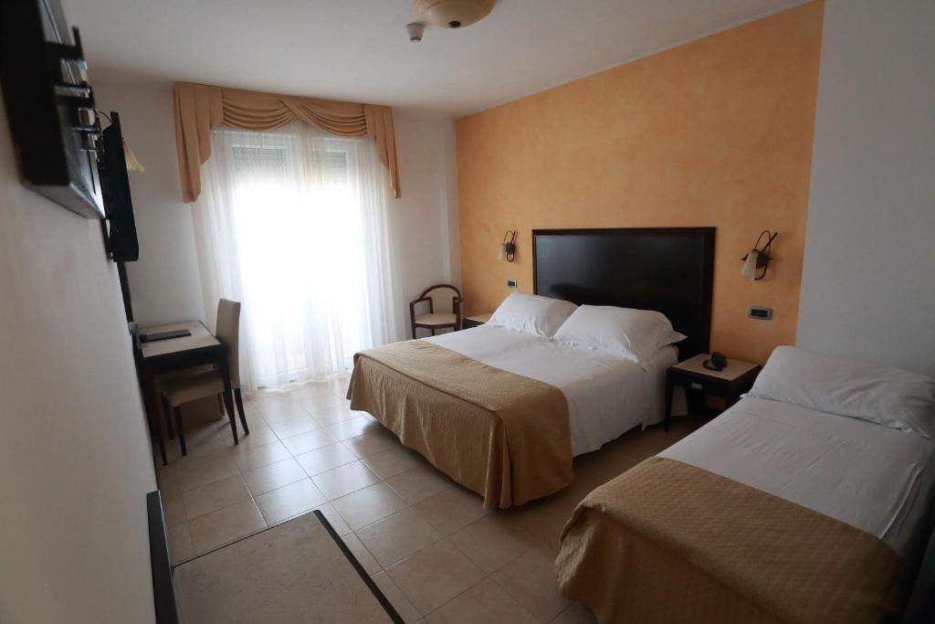 里米尼日光酒店的酒店客房设有两张床和窗户。