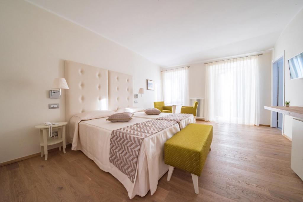 阿西西伊尔帕拉索酒店的白色卧室,配有床和绿色椅子