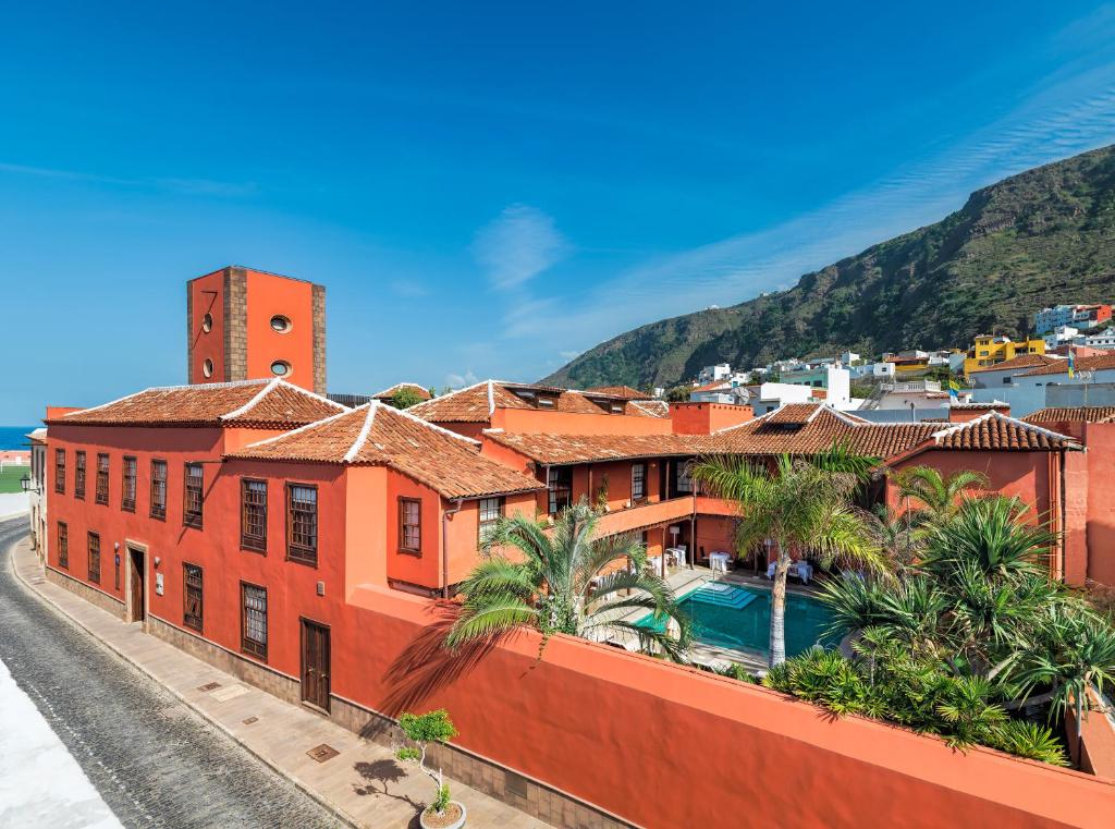加拉奇科圣罗克酒店的一座橙色的建筑,设有游泳池和山脉