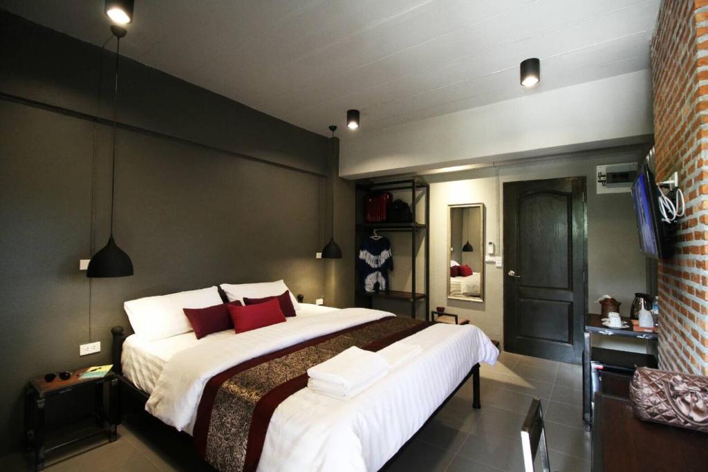 清迈度昂德林广场公寓的一间卧室配有一张大床,配有白色床单和红色枕头