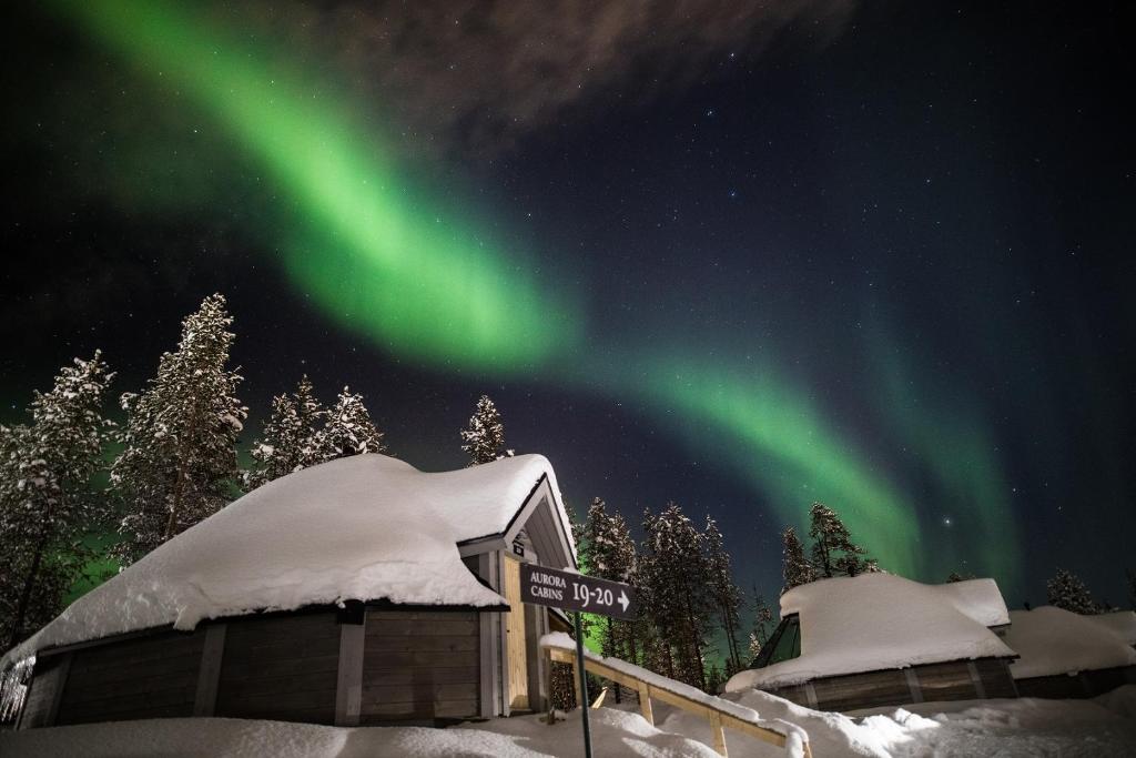 萨利色尔卡Northern Lights Village Saariselkä的雪中滑雪小屋的极光