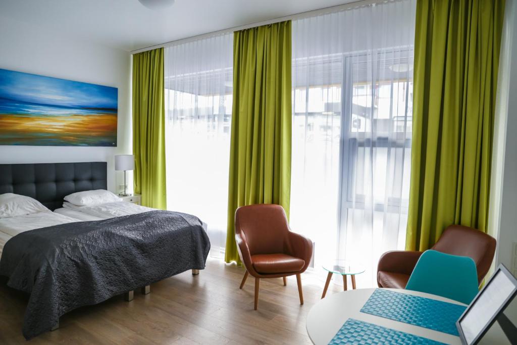 雷克雅未克Iceland Comfort Apartments by Heimaleiga的一间卧室配有绿色窗帘、一张床和两把椅子
