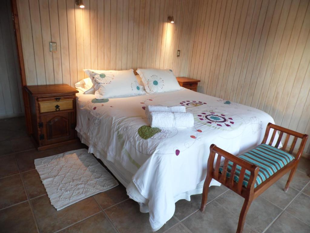 通戈伊Cabañas Urmeneta Sur的一间卧室配有一张大床和一把椅子